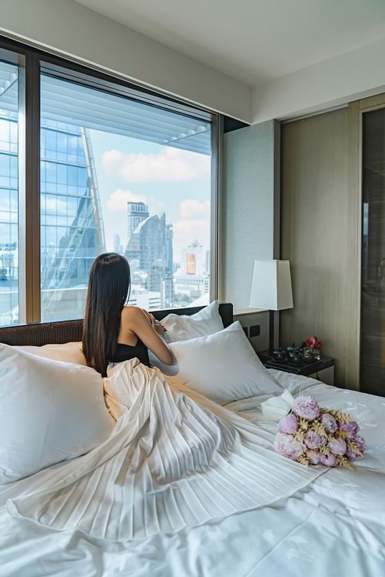 A girl on a bed in a Deluxe room & city view at Okura Prestige