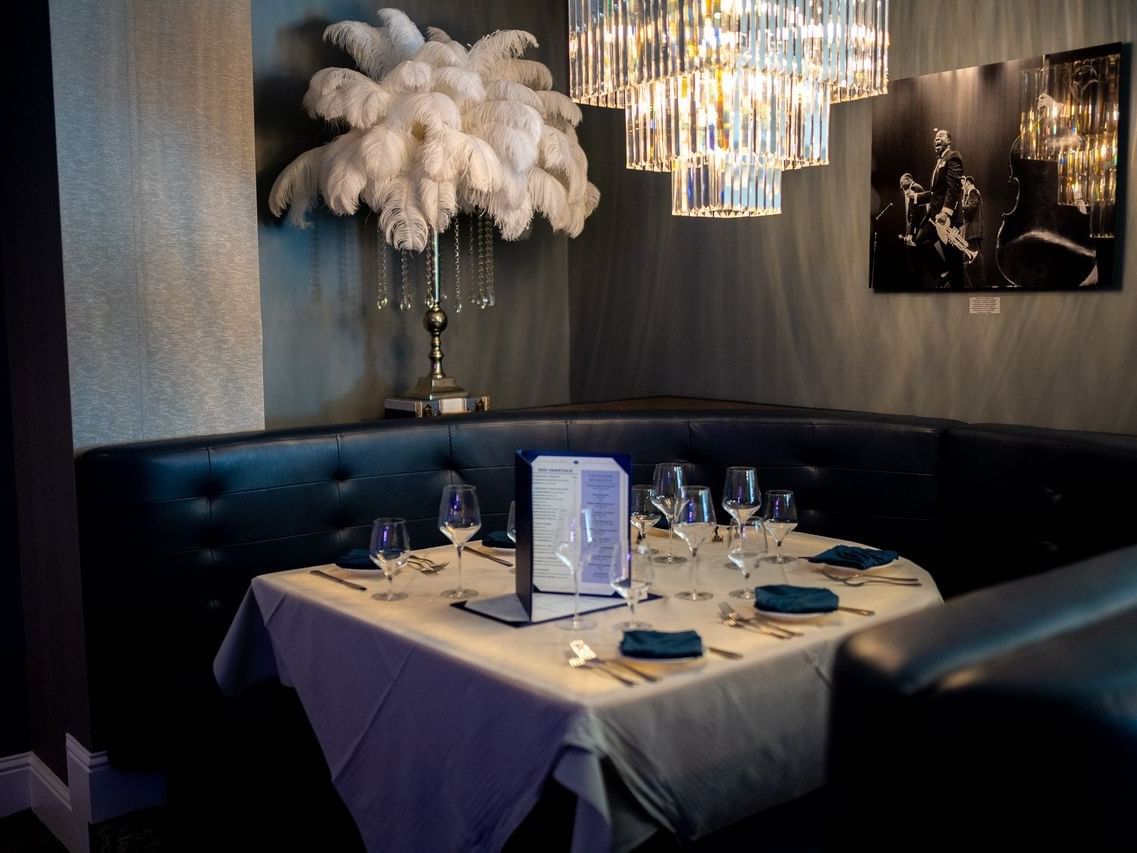 Sapphire Supper Club booth with a set table, crystal chandelier, and large feather decor near The Markham Hotel