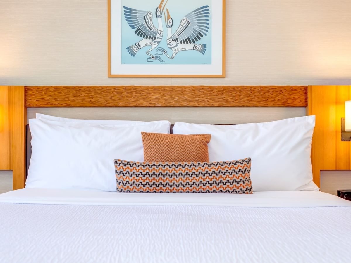 A King bed with white bedding, pillows, and a picture frame on the wall above.