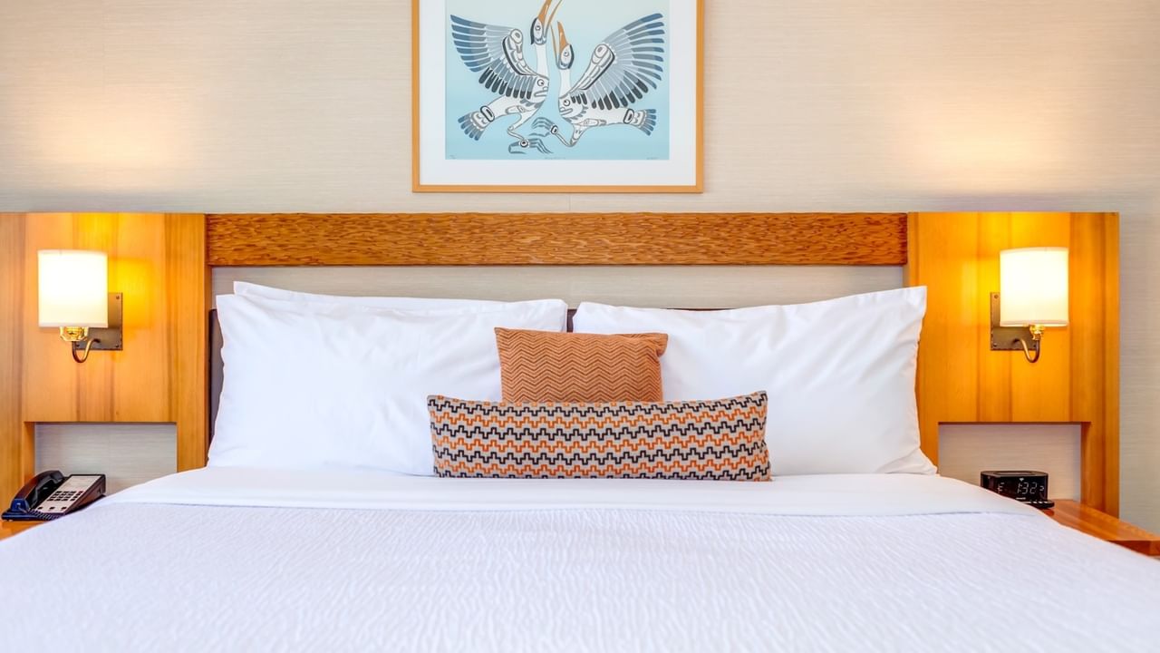 A King bed with white bedding, pillows, and a picture frame on the wall above.