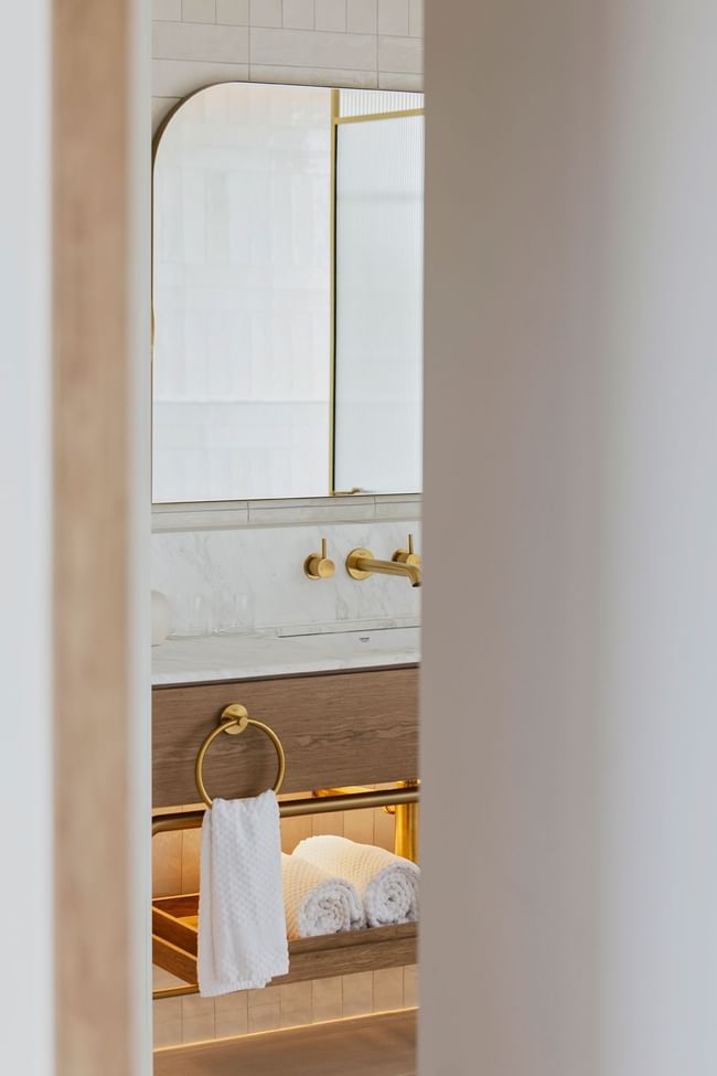 Elysium Hotels bathroom vanity glimpsed with a towel on a ring by rolled towels, a featured hotel in Neutral Bay, Sydney