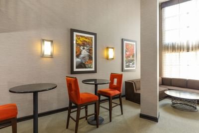 Open Area featuring orange chairs, small black tables, and nature wall art at Branson Hillside Hotel