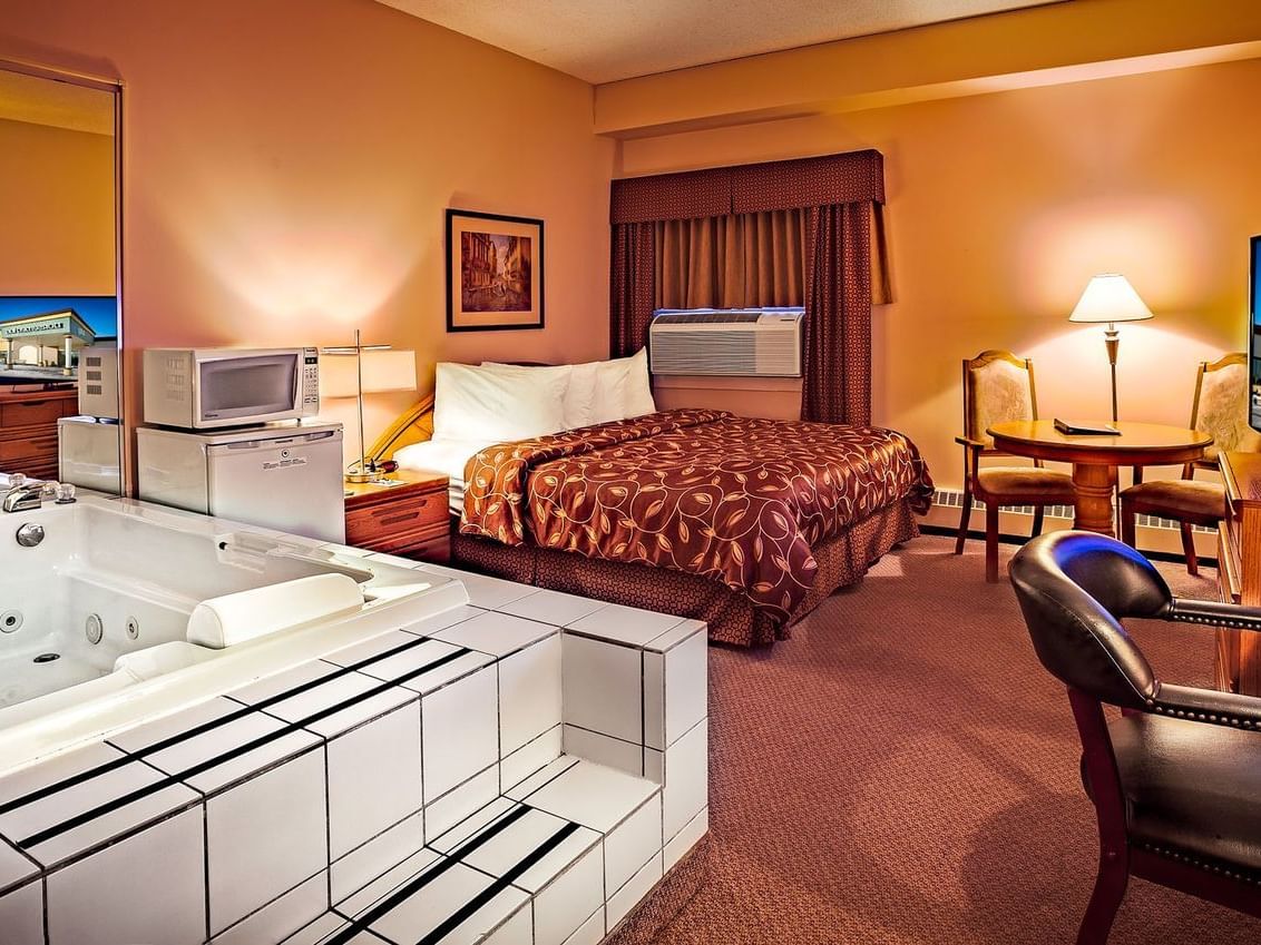 room with bed, mini fridge and hot tub