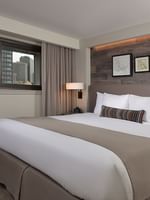 King bed by a window under framed art on a wood-paneled wall in Classic Rooms at Warwick Denver