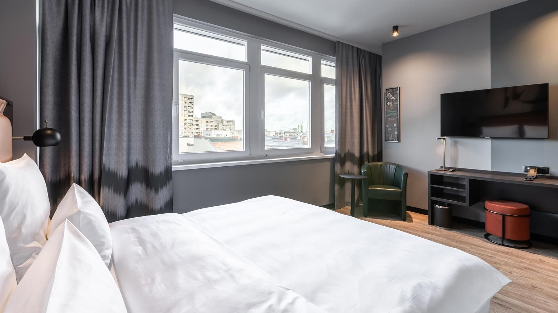 A large bed with a window overlooking the city view in the Classic Triple Room at Titanic Comfort Kurfürstendamm