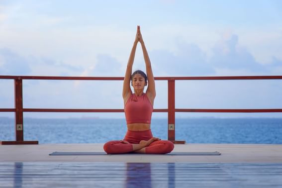 A woman performs yoga poses on a dock at Grand Park Kodhipparu, Maldives