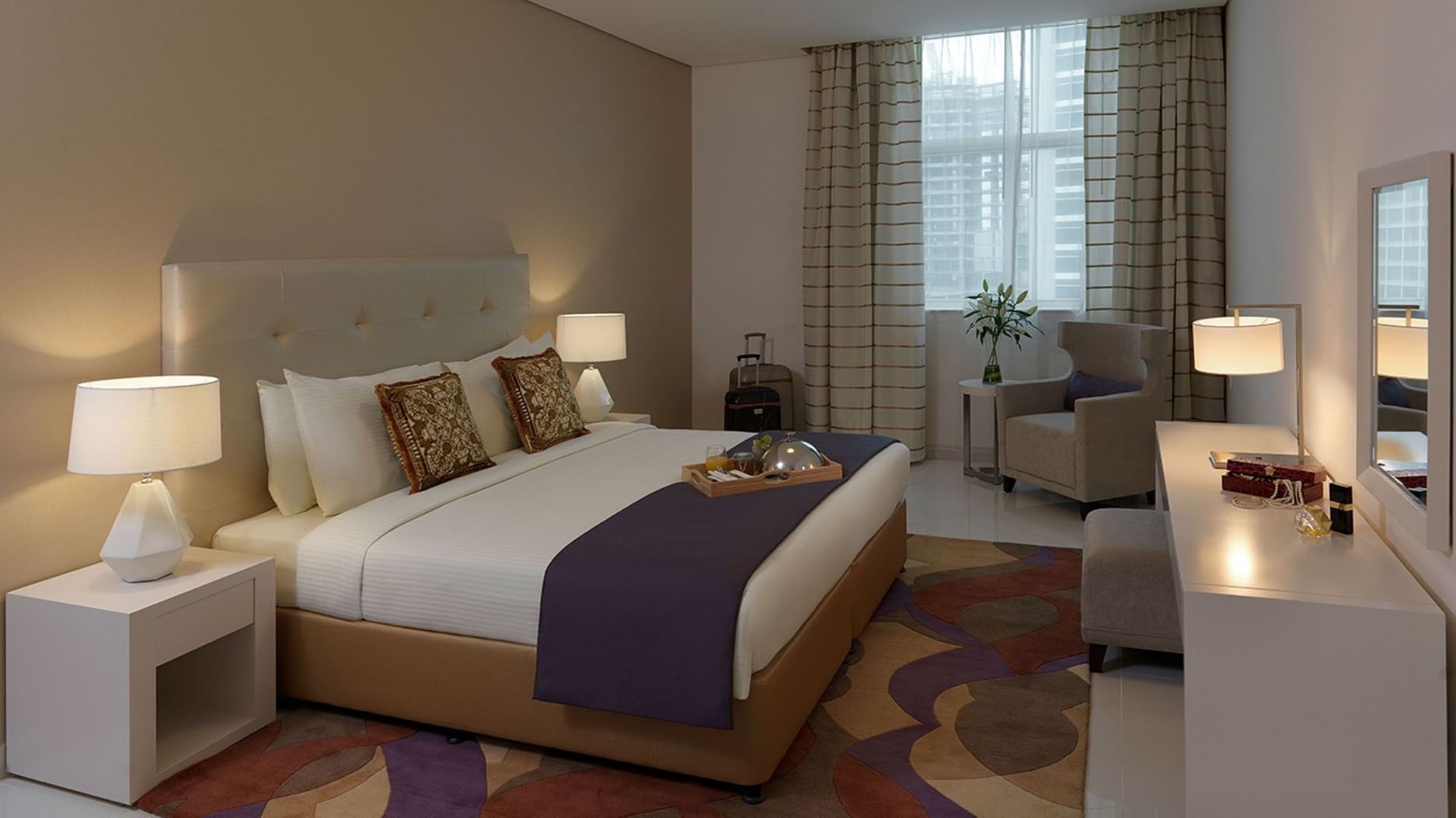 Modern interior featuring a king bed with warm lighting in Deluxe Room at DAMAC Maison Cour Jardin