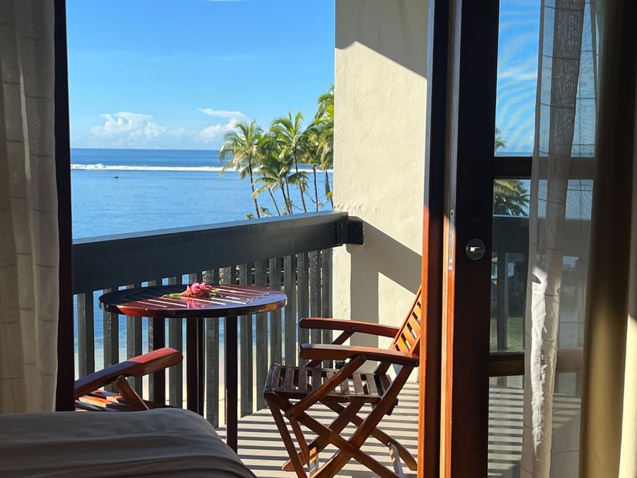 Beach view from balcony with wooden chairs and table at Warwick Fiji Resort and Spa.