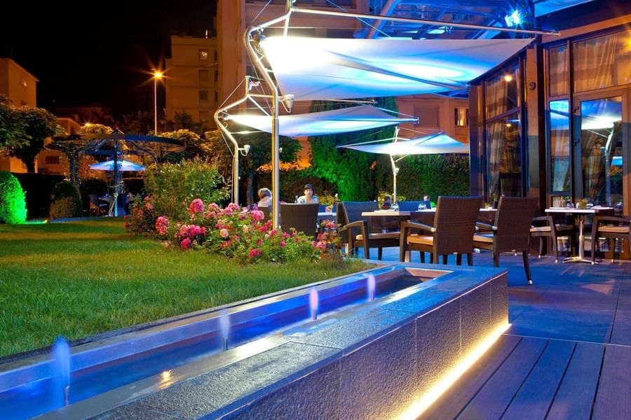 The Lounge Bar & Terrace with wicker chairs, modern awnings, & blue lighting at Warwick Reine Astrid - Lyon