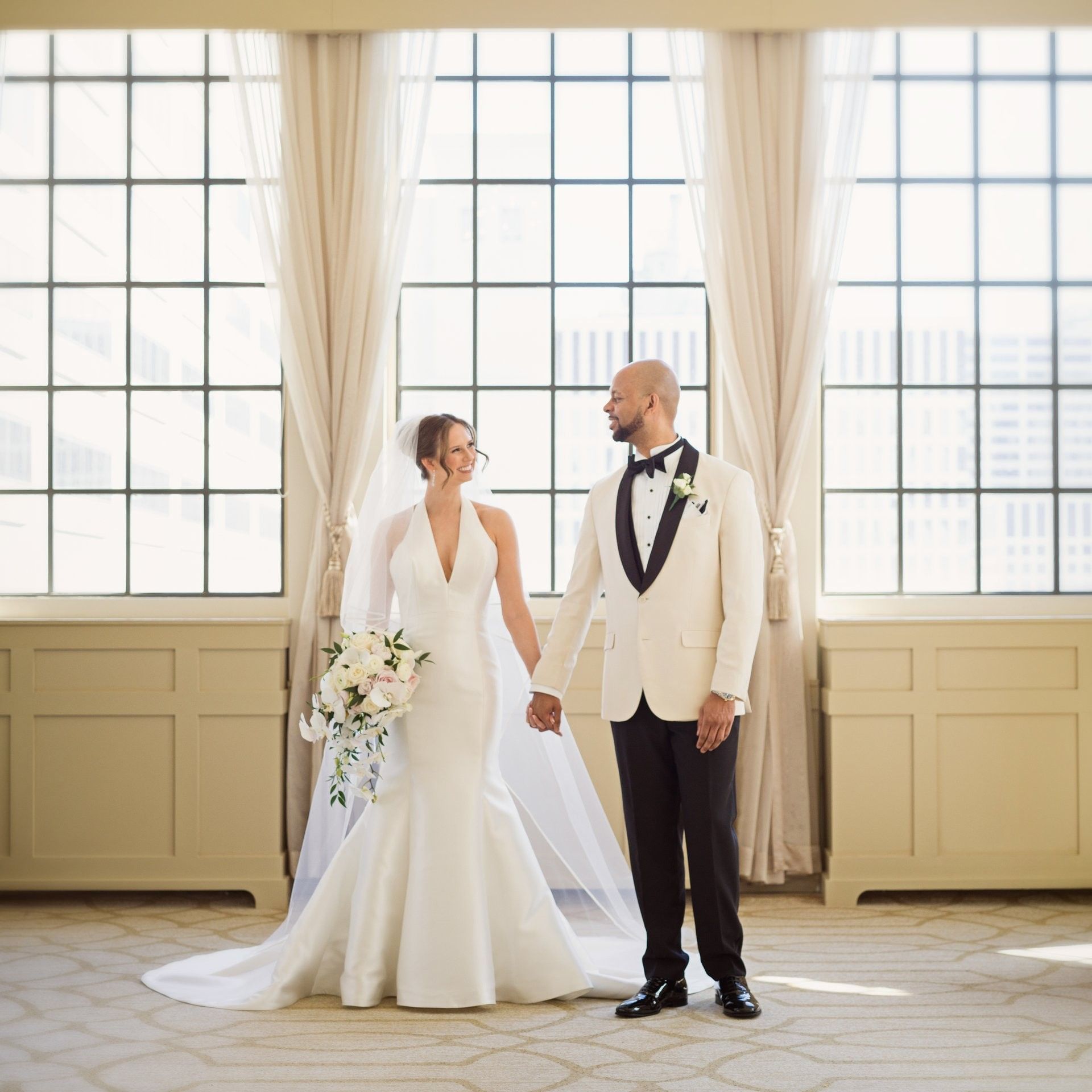 Bride and groom holding hands near large windows at Warwick Allerton Chicago