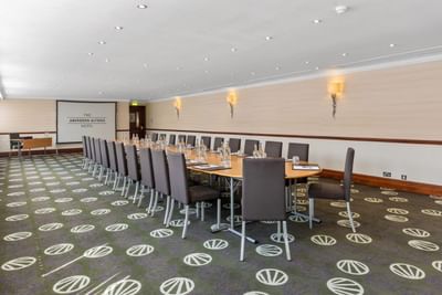 A long conference table with chairs in Grandholm Suite at The Aberdeen Altens Hotel with a projector screen