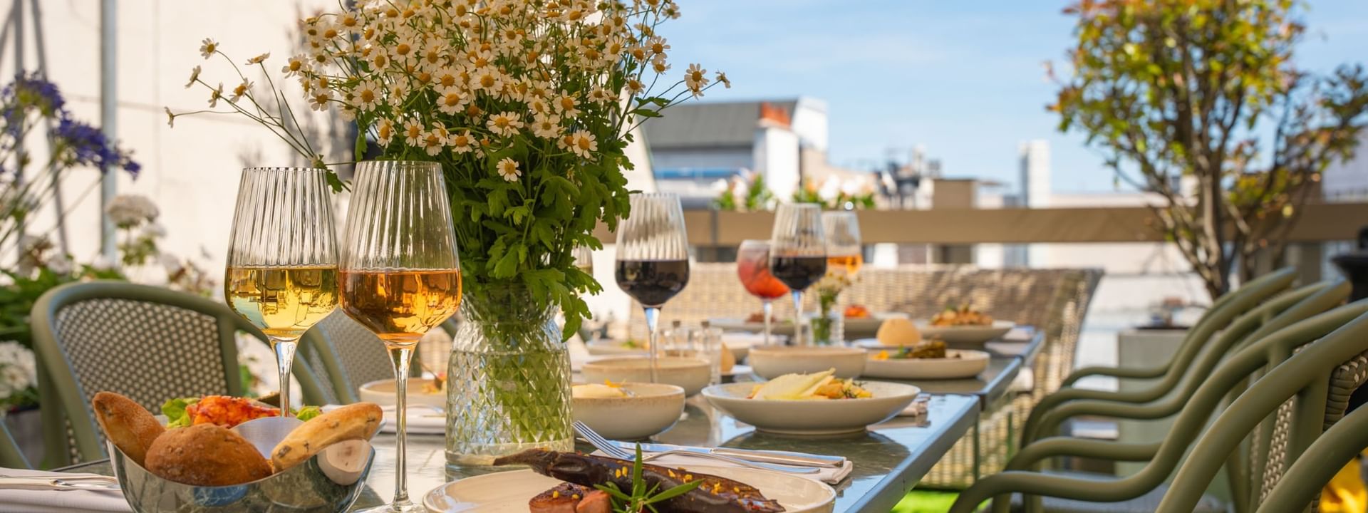 Table dressée avec plats gastronomiques et verres de vin sur la Terrasse Le W au Warwick Paris Champs-Elysées