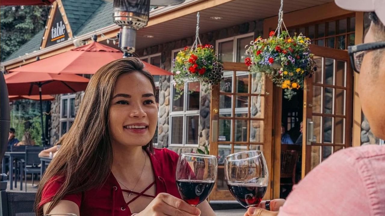 Two people enjoying wine on a sunny patio at Coast Hotel restaurant.