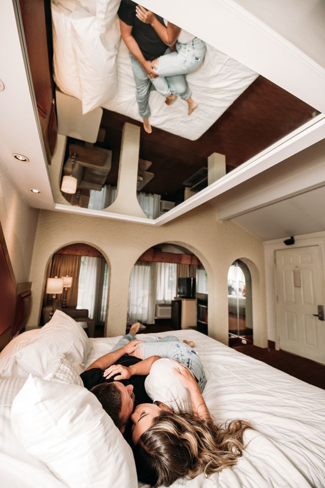 Couple relaxing on a bed, their reflection visible in the mirrored ceiling at Cove Pocono Resorts
