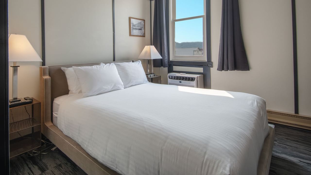 Hotel room with queen bed, night stand, lamp, and window
