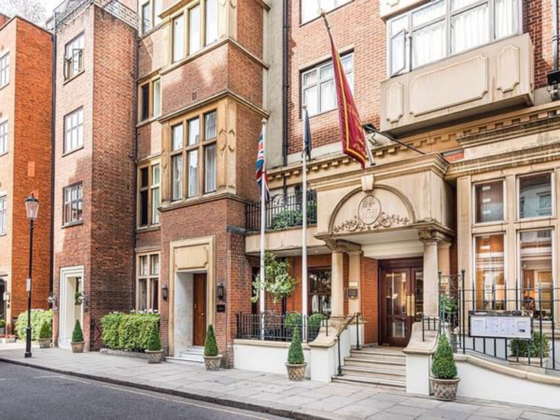 Exterior view featuring a red flag waving over the stone entrance at The Capital Hotel, Apartments and Townhouse