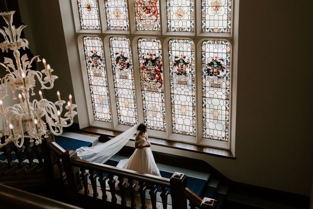 A bride on the Mansion House staircase beneath the stained-glass windows