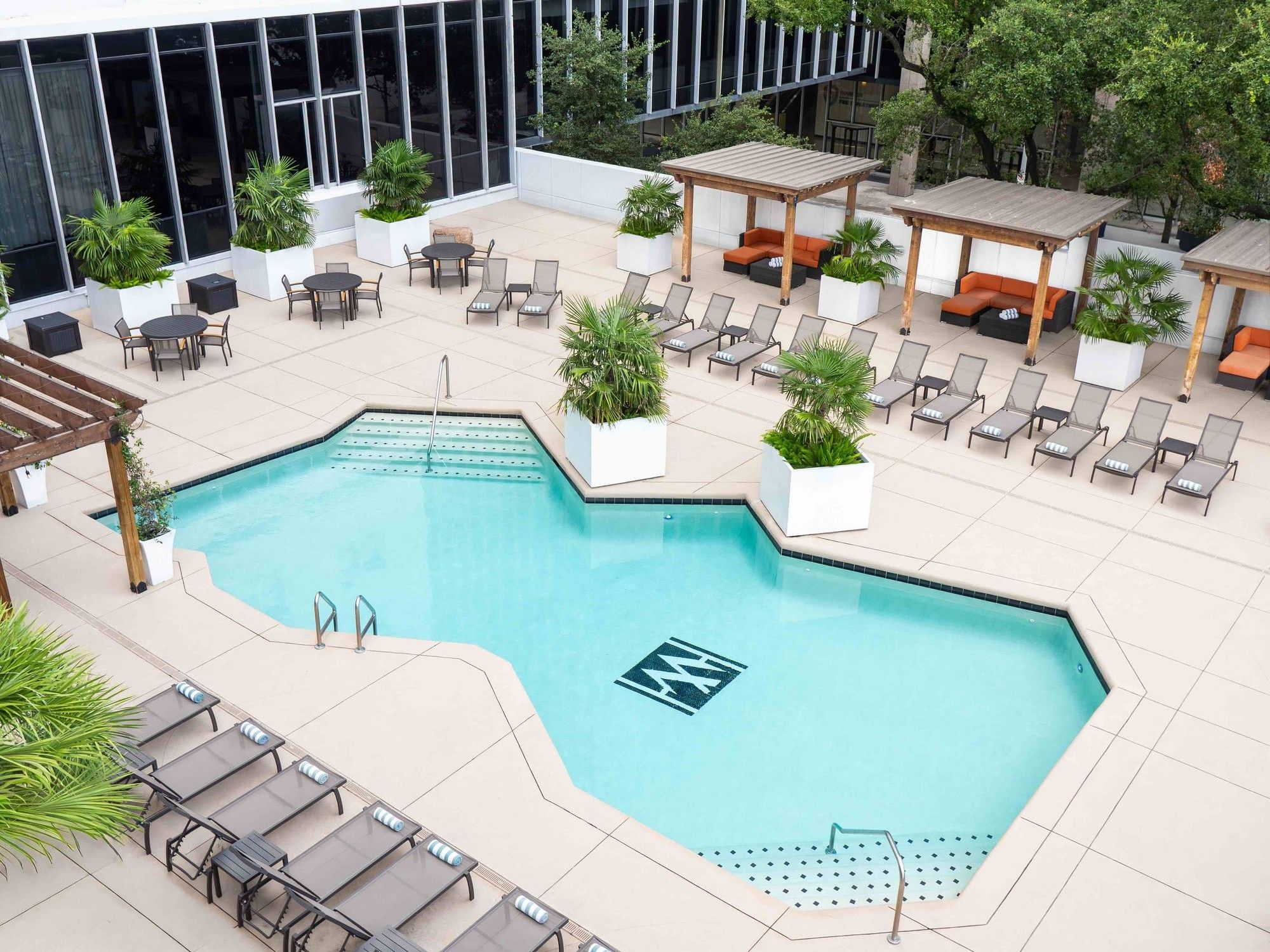High-angle view of the sparkling rooftop pool surrounded by chic cabanas at The Whitehall Houston