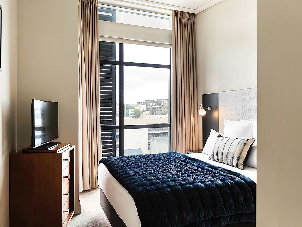 TV facing bed by the window in City View One Bedroom Suite at The Sebel Auckland Viaduct Harbour