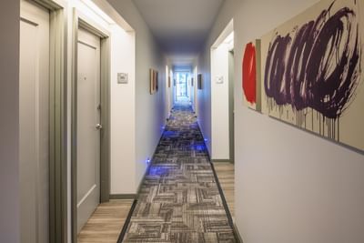 Modern hallway, featuring abstract purple and red artwork placed on the walls by guest room doors at Hotel Keen