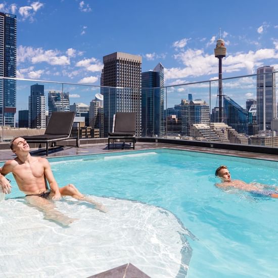 Two men relaxing in the Rooftop Pool at Pullman Sydney Hyde Park