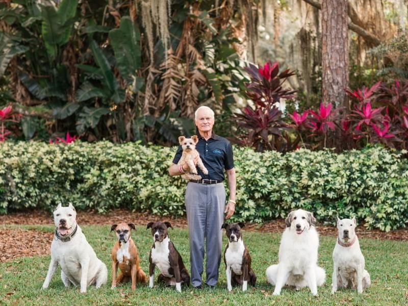 Man with his dogs posing on a lush green lawn at Rosen Inn International