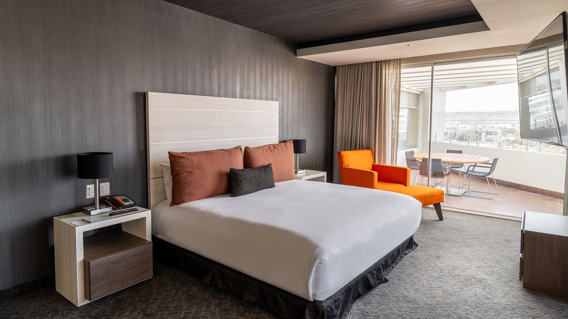 Nightstands & cozy lounger by the bed in the King Presidential Suite with a private balcony seating area at Real Inn Tijuana