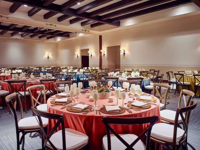 Elegantly set round tables with tableware and wine glasses in Arcos 3 event room at Hacienda Del Mar Los Cabos in Cabo San Lucas.