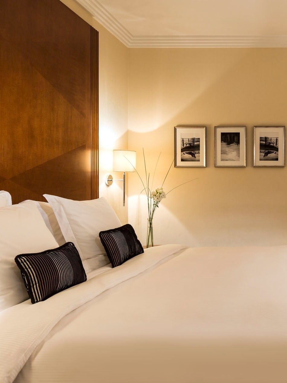 White bed by a desk under a tall lamp with framed art on the wall in Classic Room at Warwick Geneva