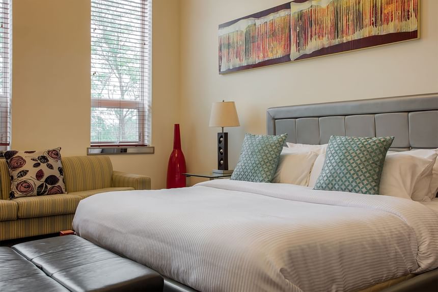 king bed in refresh with couch in behind and original artwork on