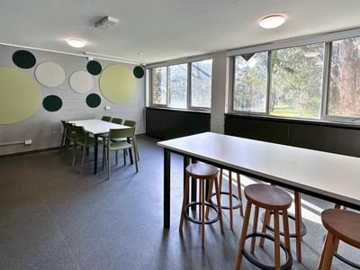 Dining area with tables, chairs, and acoustic panels on the wall at La Trobe University – Menzies College.