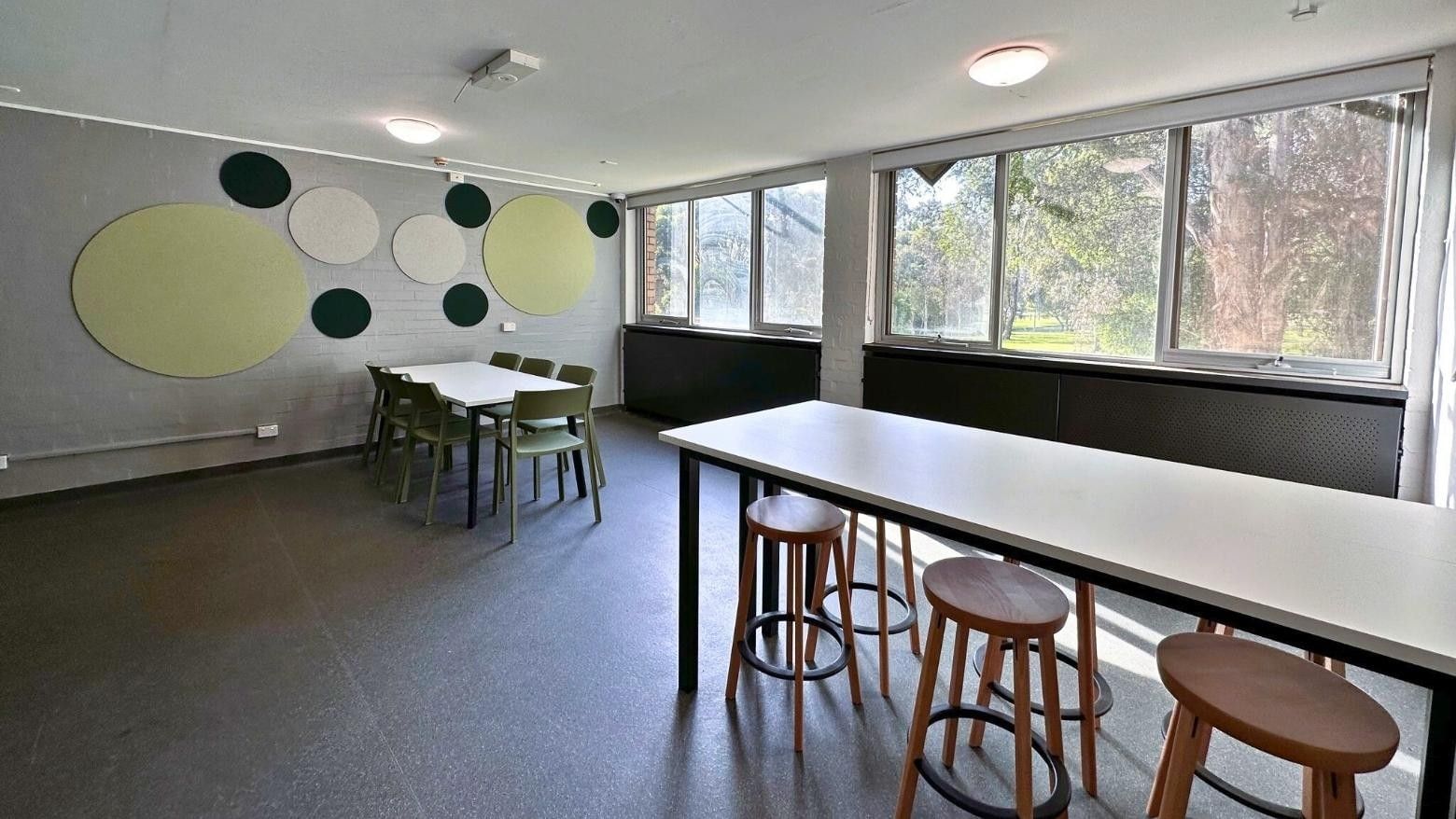 Dining area with tables, chairs, and acoustic panels on the wall at La Trobe University – Menzies College.