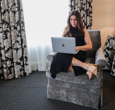 A girl on a chair working on a laptop in a room at Eliot Hotel
