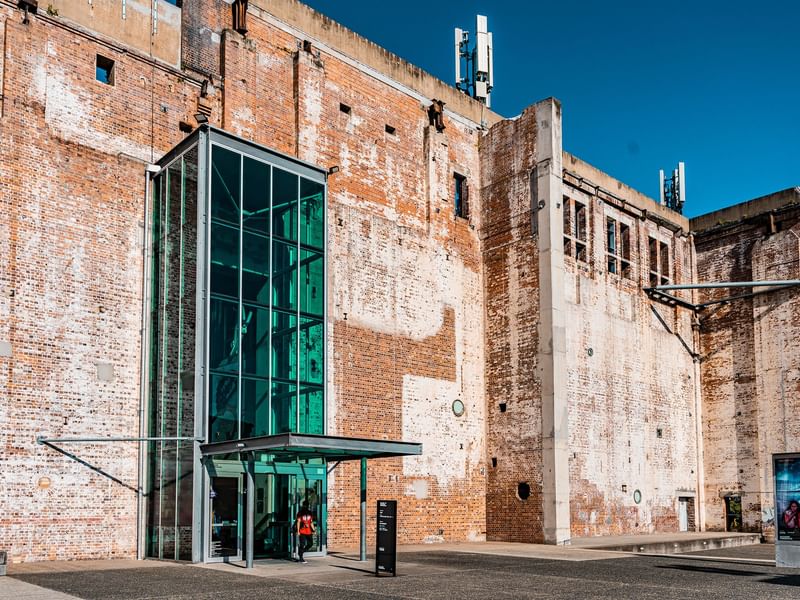 Historic brick building with modern glass entrance at Brisbane Powerhouse under clear blue sky.