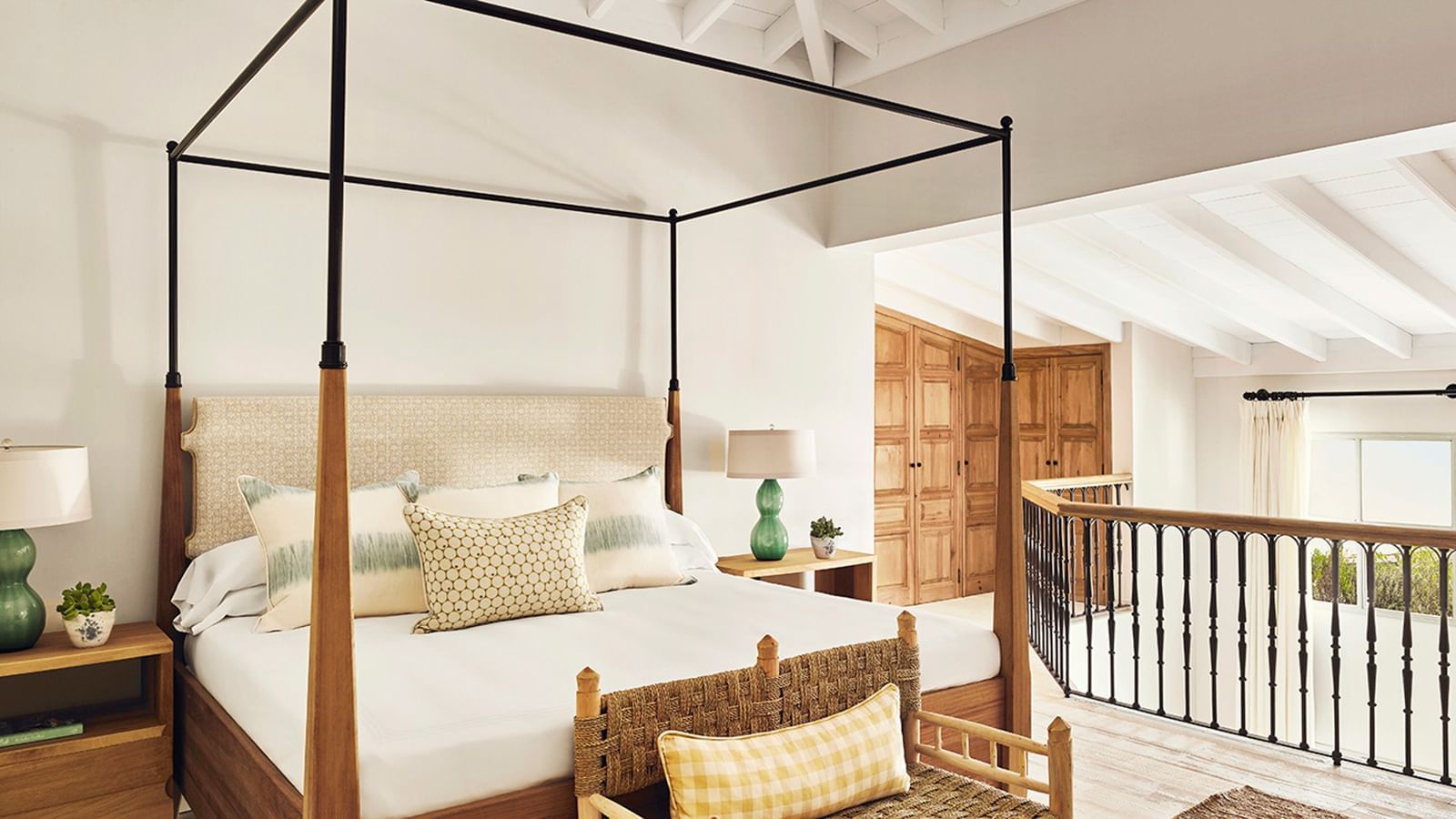 Bedroom with a wood four-poster bed near a mezzanine overlooking a set of wood doors at Marbella Club