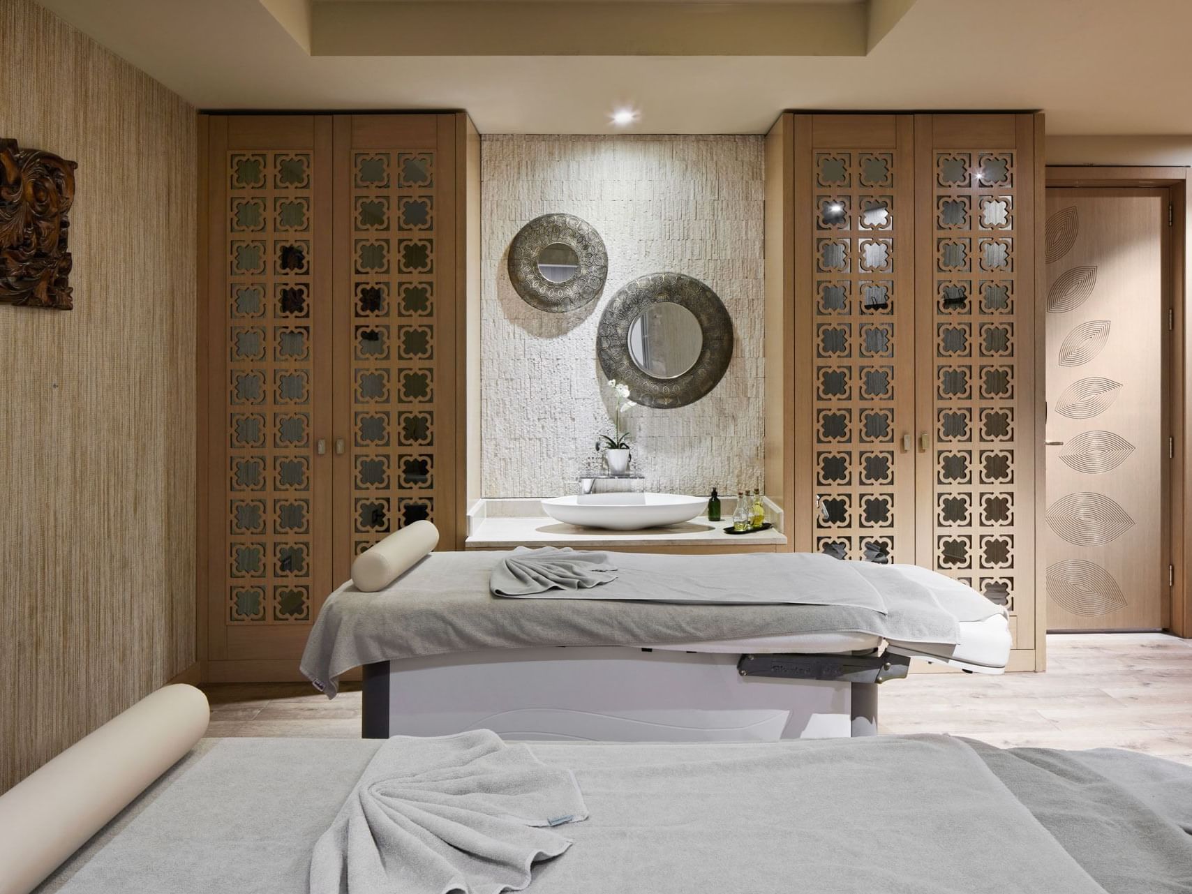 Elegantes Spa-Zimmer mit zwei Liegen, dekorativen Details und Waschbecken – Titanic Chaussee Berlin.