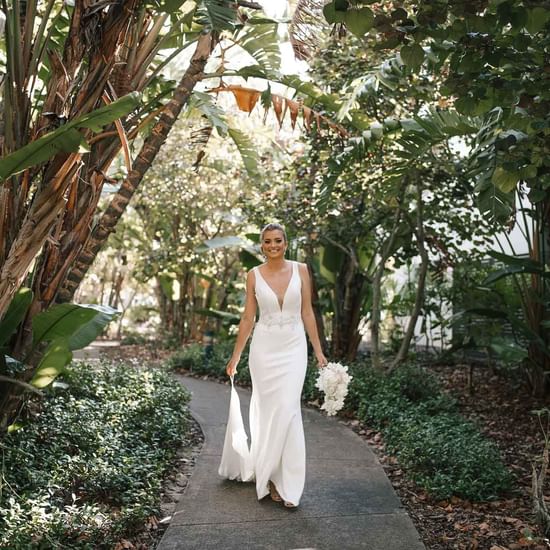 Bride walking with a flower bouquet in the garden area at Pullman Magenta Shores