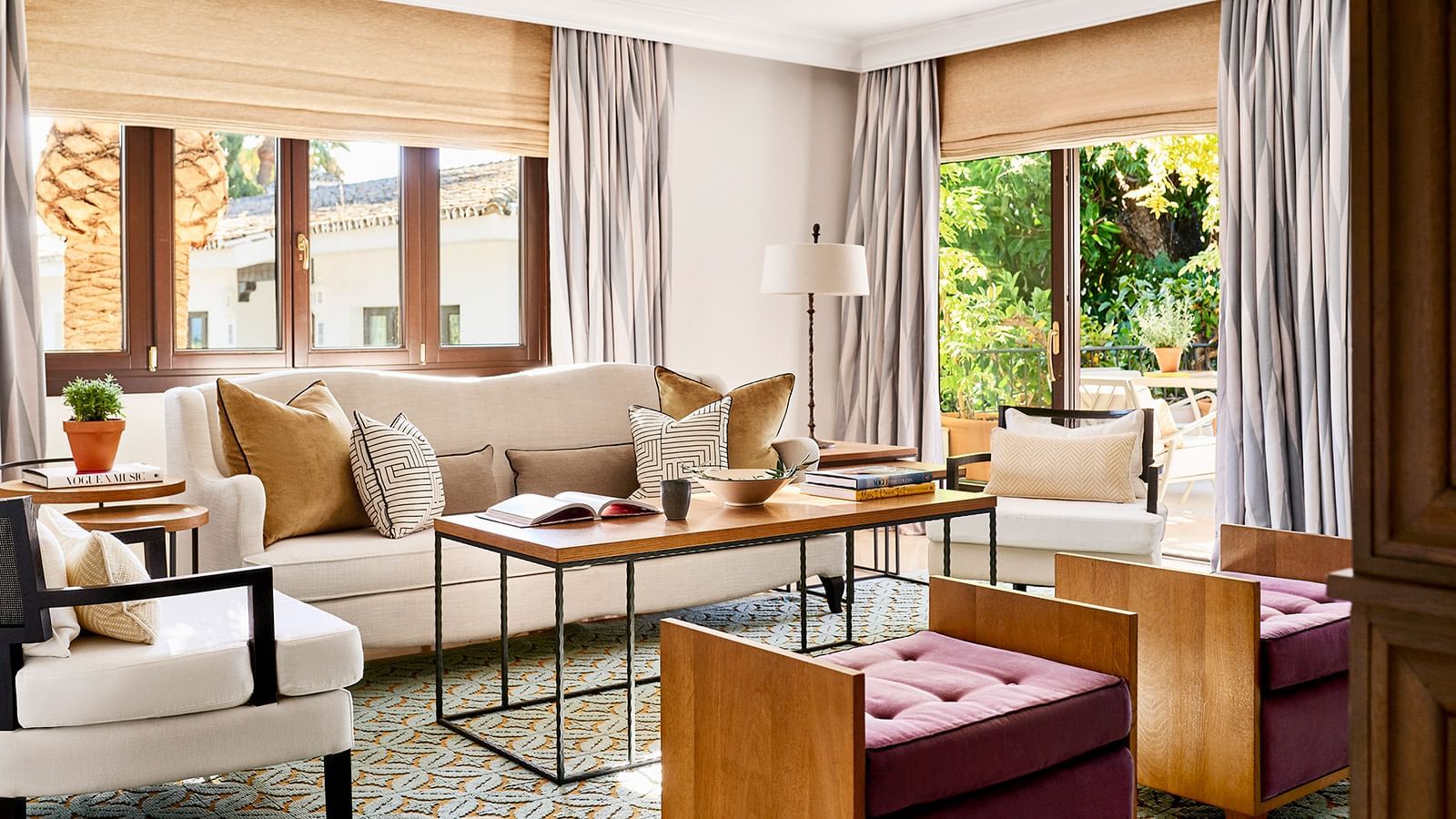 Sun-drenched Conde Rudi living room with a sofa, geometric rug, & windows opening to a garden patio at Marbella Club