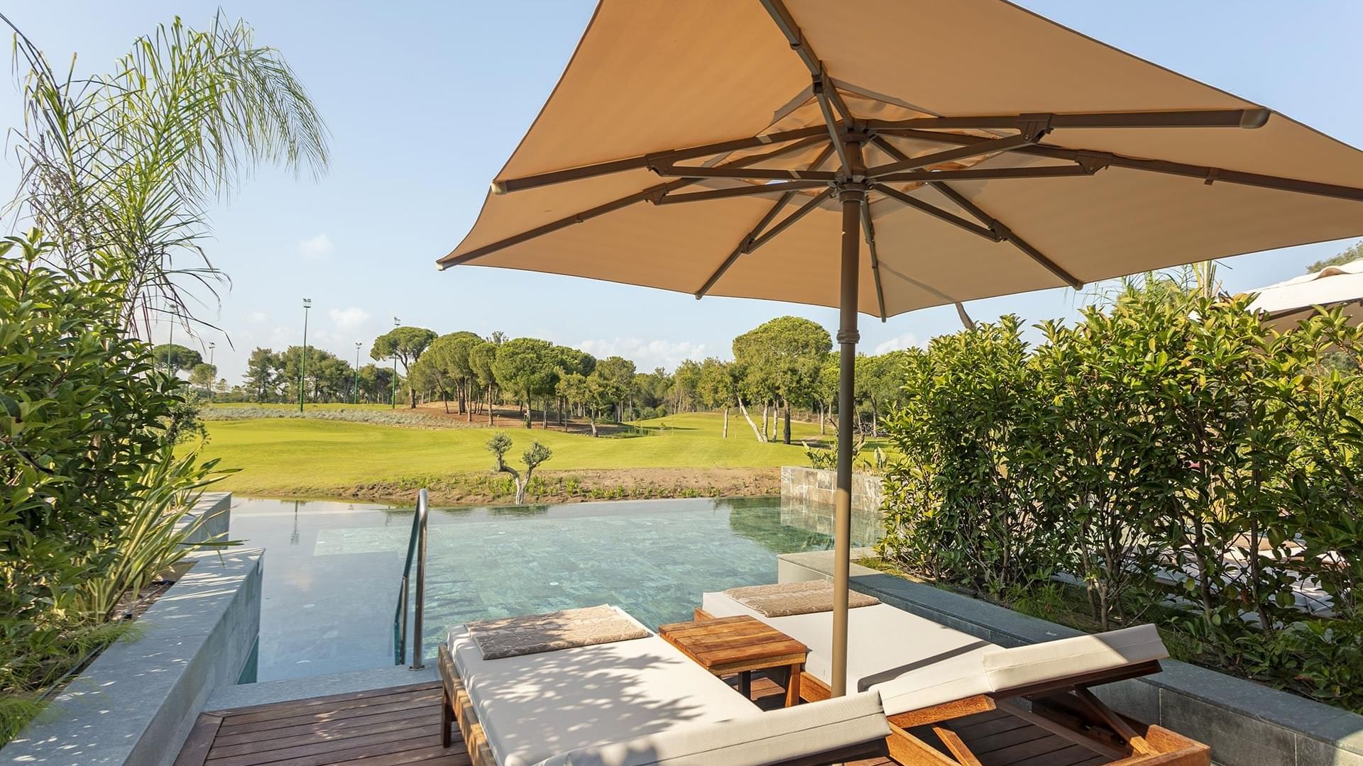 Poolside loungers with patio umbrella at Lagoon Golf Swim-up Room in Cullinan Belek
