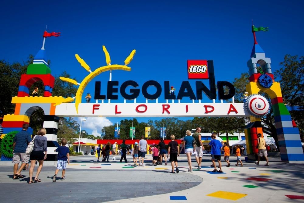 The large entry gates to LEGOLAND Florida, with LEGO castle towers and a crowd walking into the theme park.
