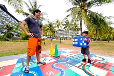 A man and a kid playing life size snake and ladders