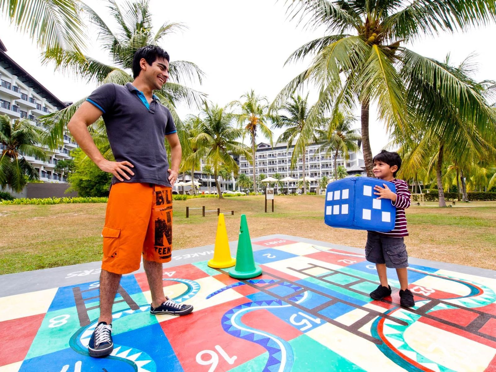 A man and a kid playing life size snake and ladders
