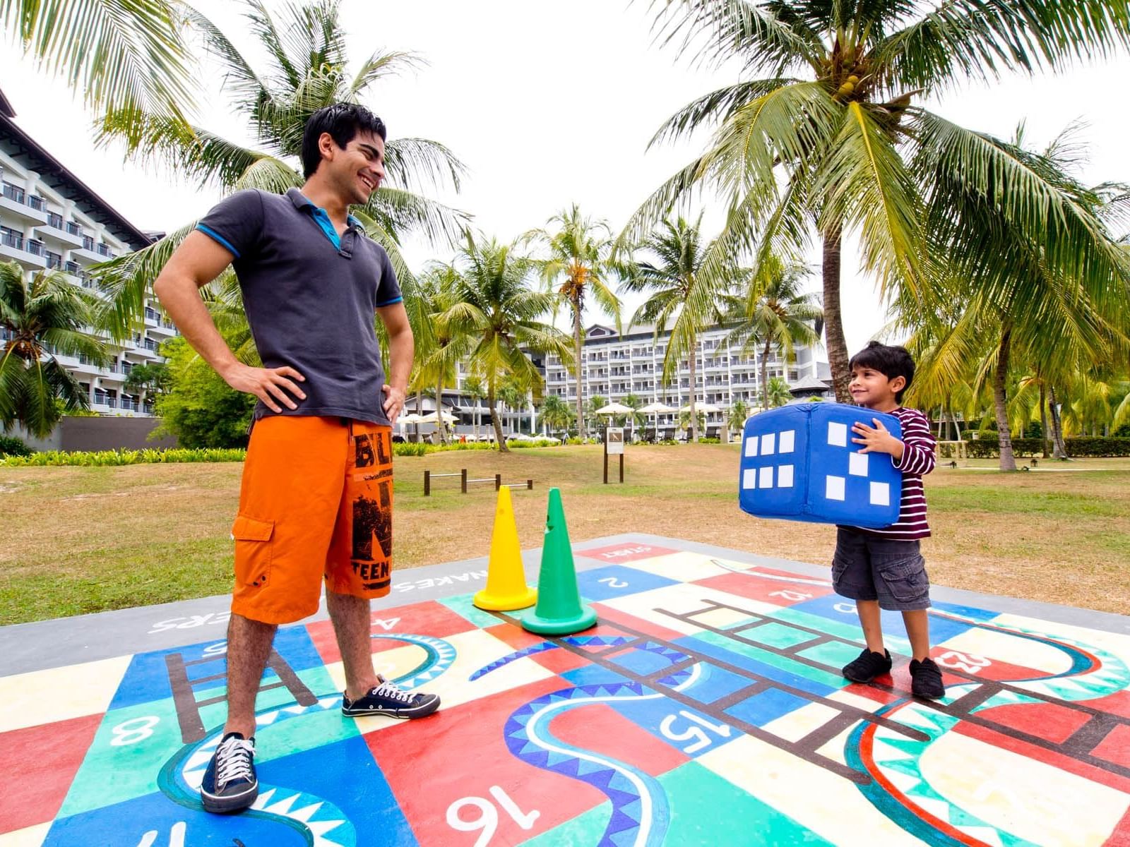 A man and a kid playing life size snake and ladders