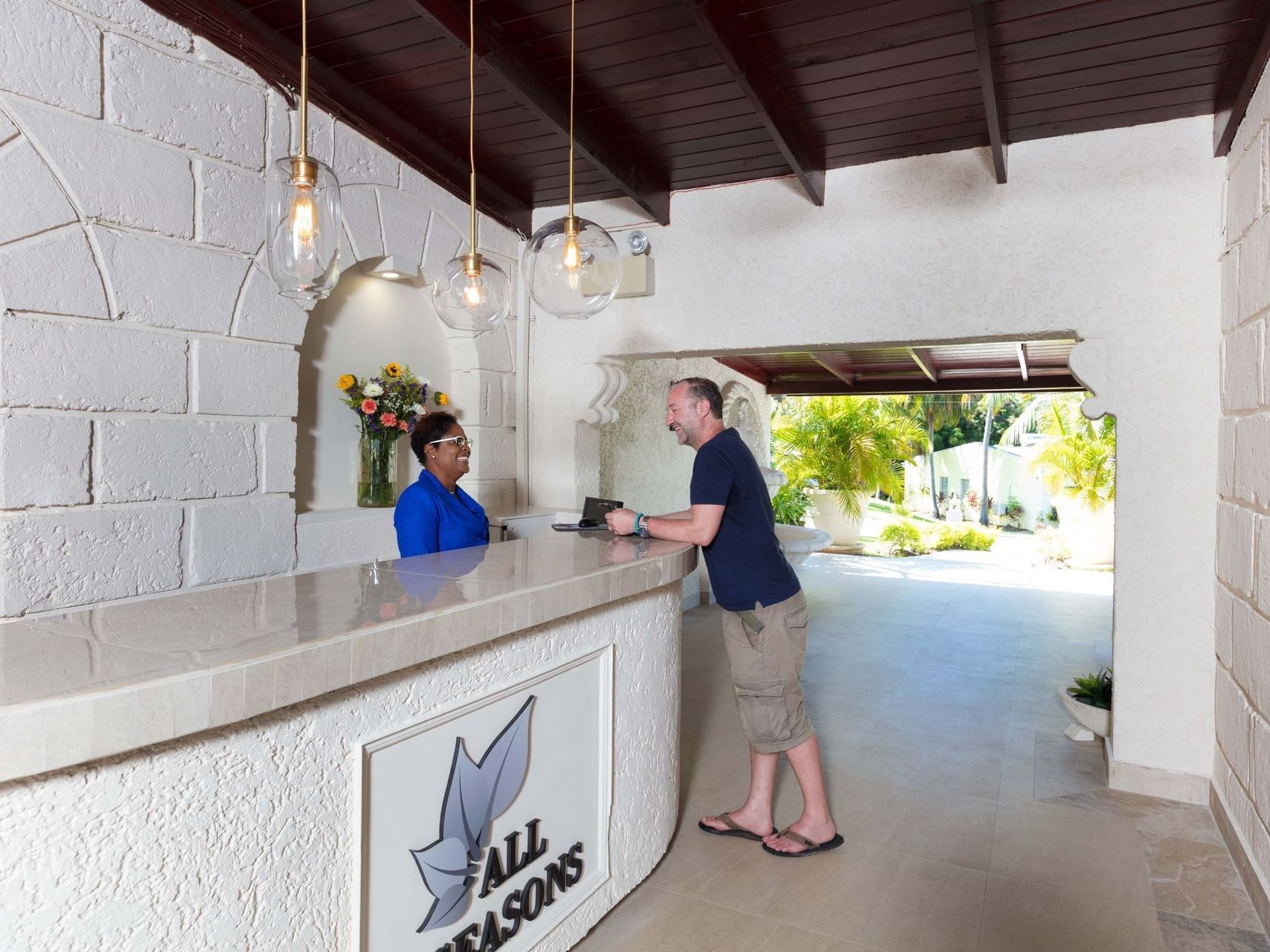 A guest interacting with a receptionist at the check-in counter in All Seasons Resort Europa