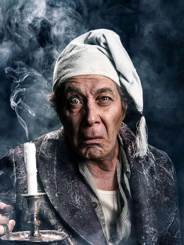 Eugene Gilfedder in old clothing holding candlestick surrounded by smoke for A Christmas Carol poster used at Sofitel Brisbane Central