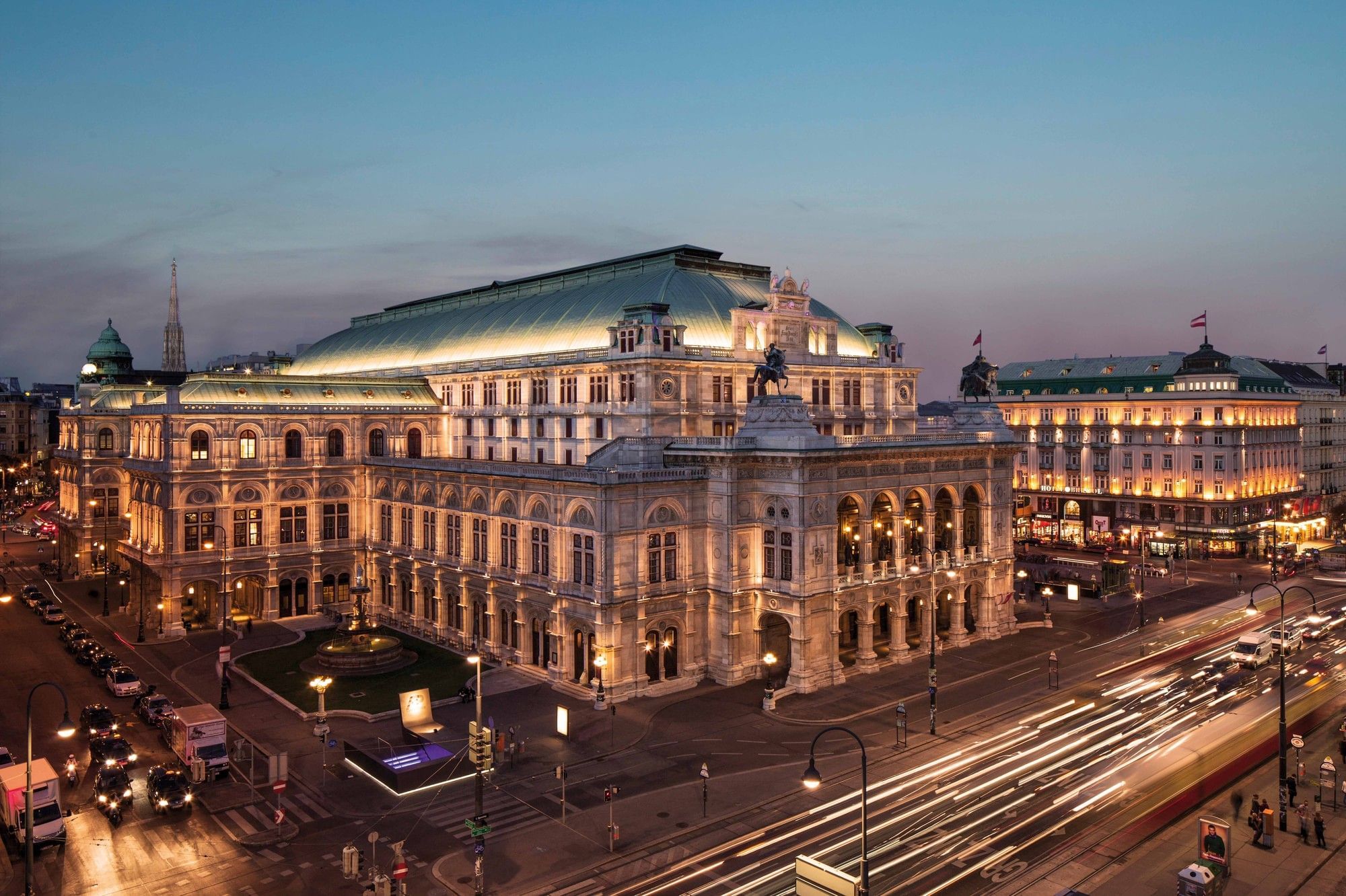 Vienna State Opera at dusk in the city center of Vienna with illuminated facade and urban traffic