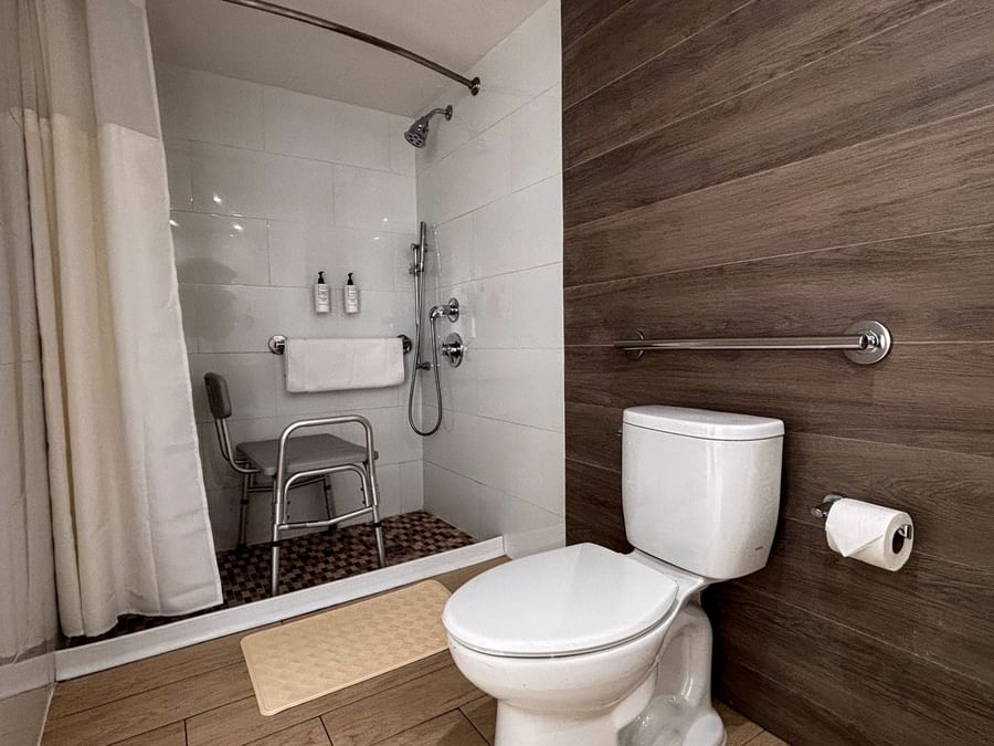 Roll-in shower by a shower chair under a grab bar near a toilet in Island View Accessible at Warwick Paradise Island Bahamas