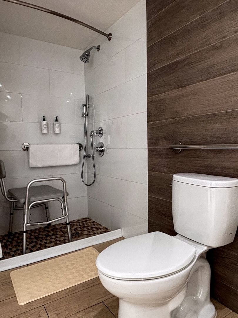 Roll-in shower by a shower chair under a grab bar near a toilet in Island View Accessible at Warwick Paradise Island Bahamas