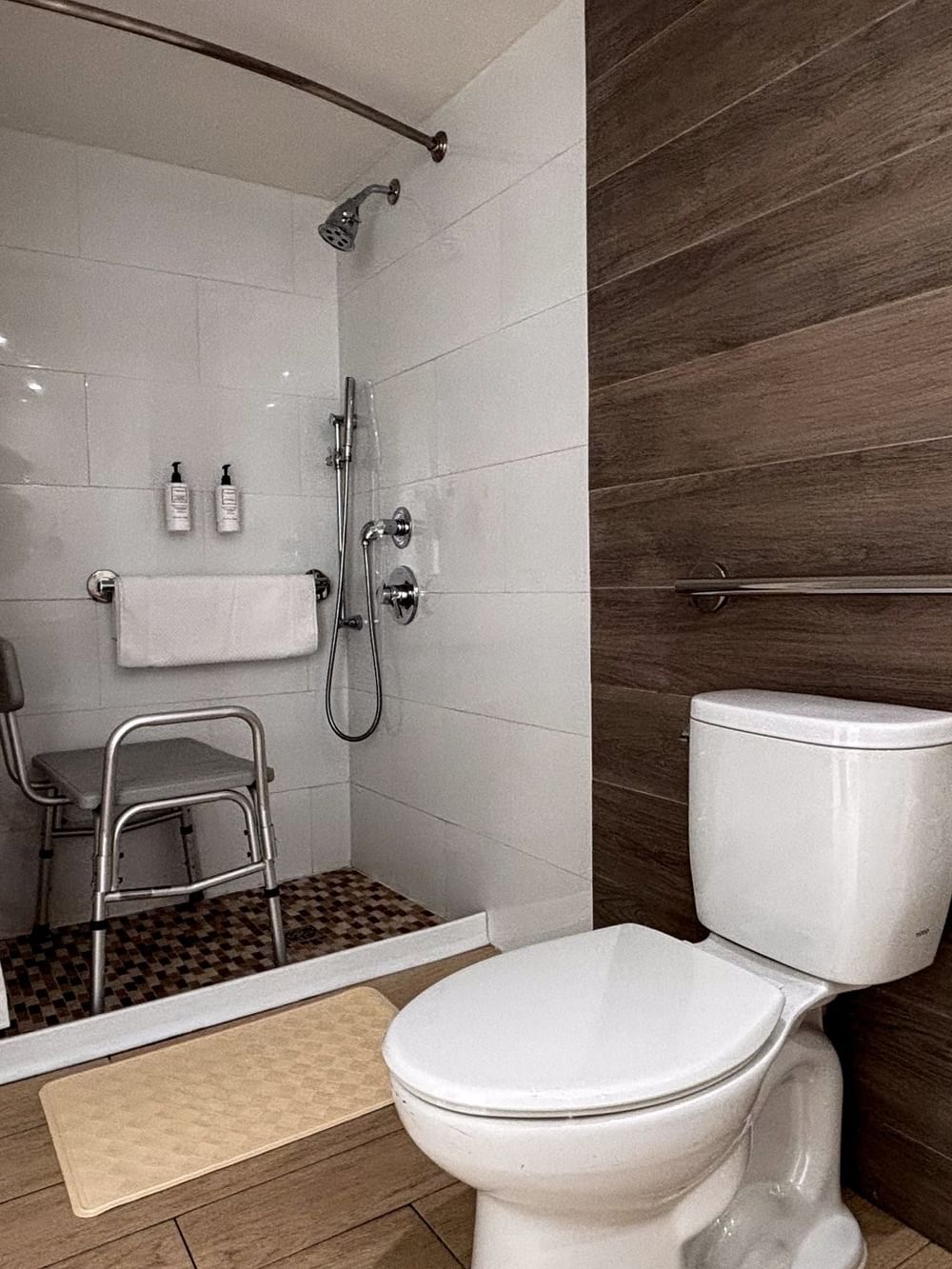 Roll-in shower by a shower chair under a grab bar near a toilet in Island View Accessible at Warwick Paradise Island Bahamas