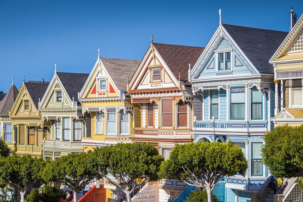 Victorian houses by green trees under a clear blue sky near Warwick San Francisco